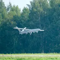 An unmanned aerial vehicle is pictured flying beneath a tree line.