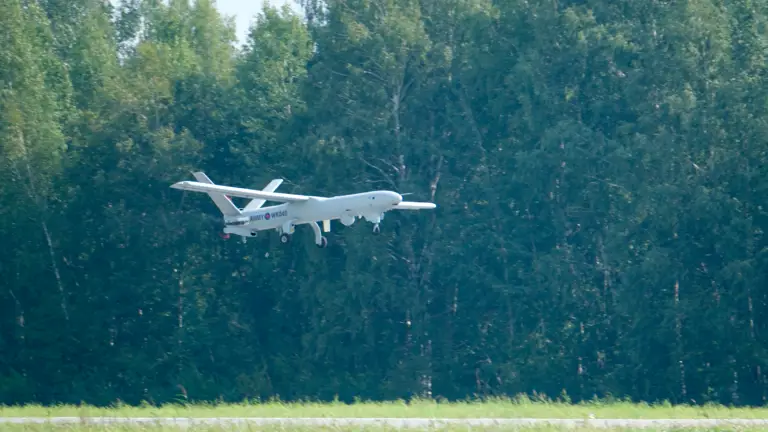 An unmanned aerial vehicle is pictured flying beneath a tree line.
