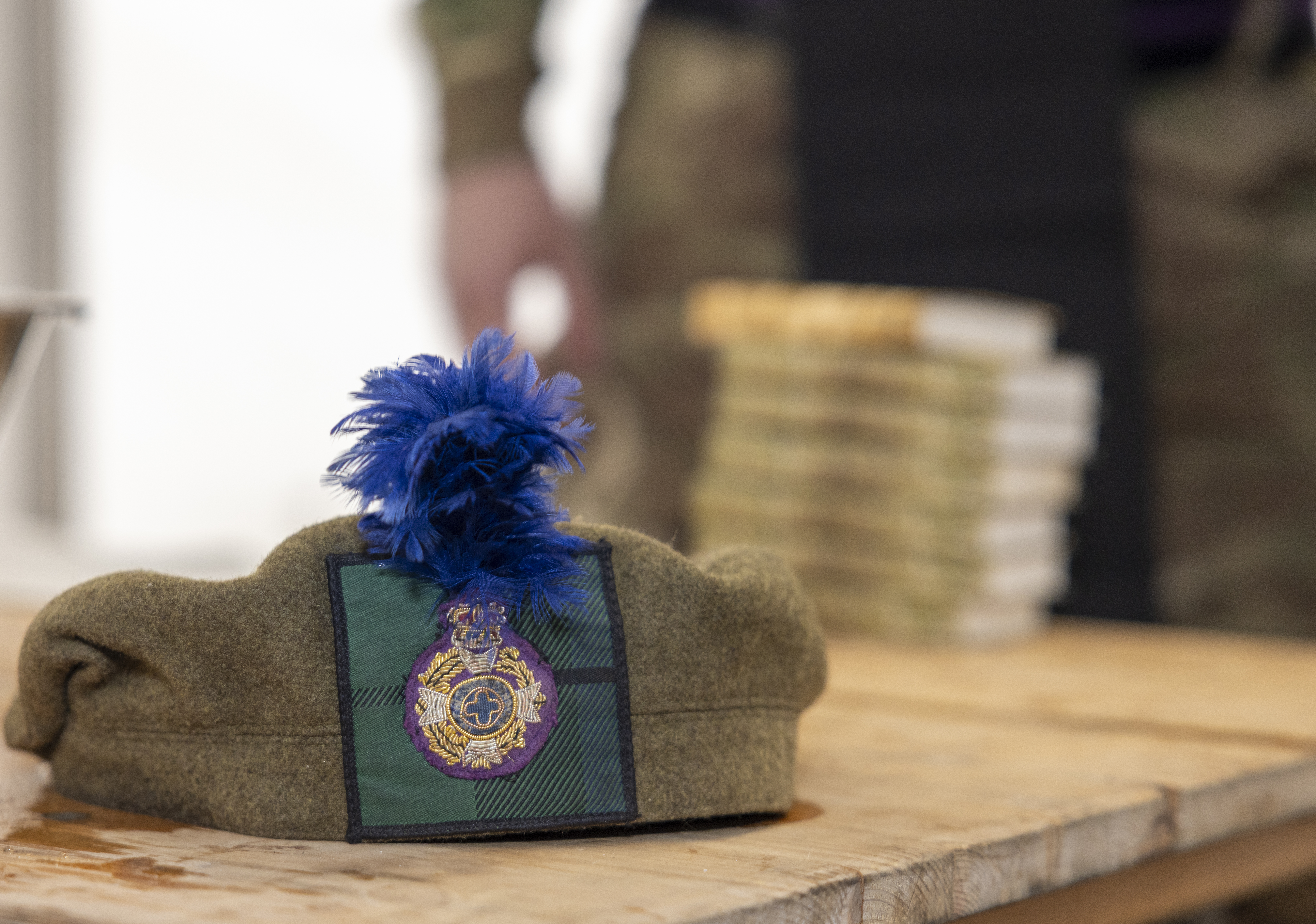 A close up of a green Army headdress with a blue ploom.