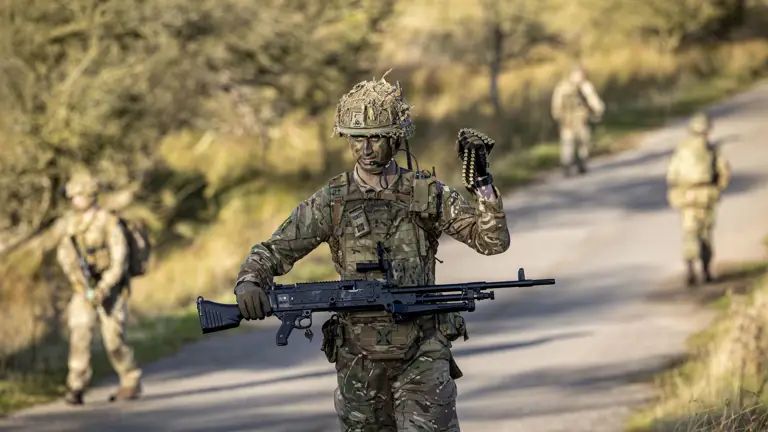 A man in uniform is pictured carrying a weapon and ammunition.