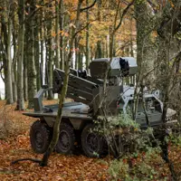 A green uncrewed vehicle sits in a woodblock.