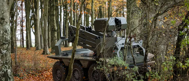 A green uncrewed vehicle sits in a woodblock.