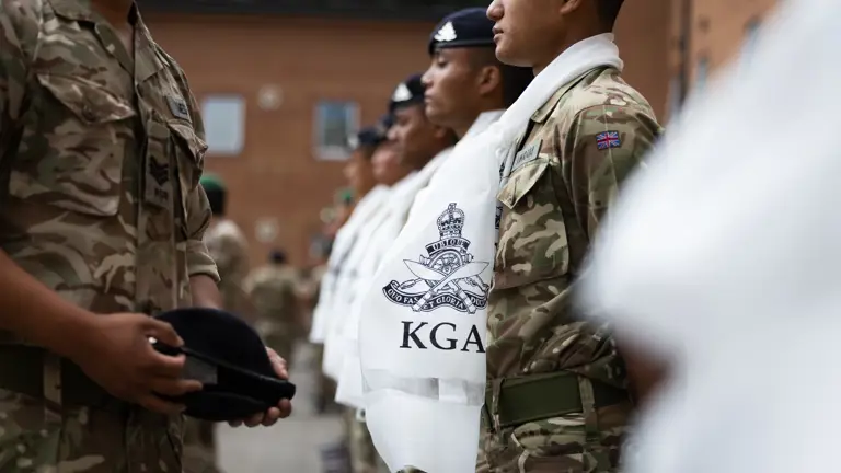 A British Army office is placing a new unit cap badge on a beret for presenting to a soldier.