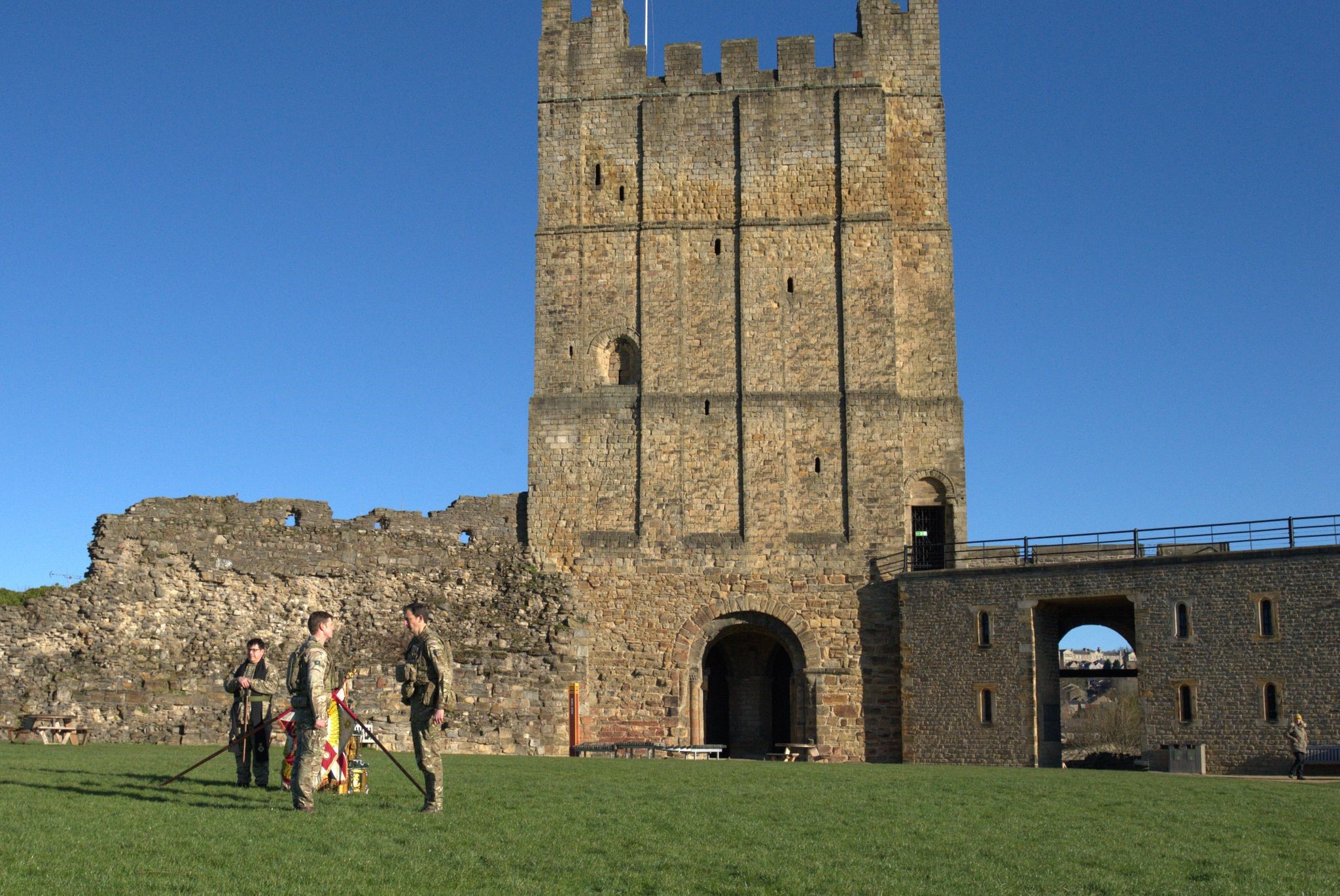 Four soldiers in uniform are pictured against the backdrop of Richmond castle. 