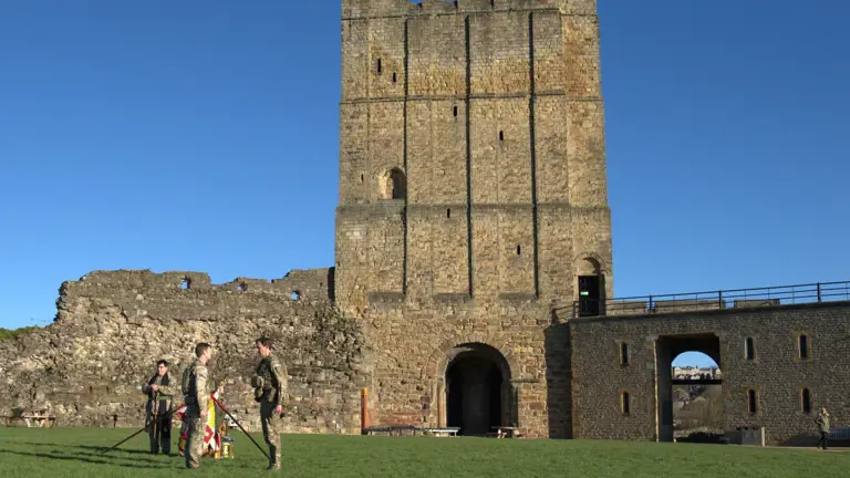 Four soldiers in uniform are pictured against the backdrop of Richmond castle.