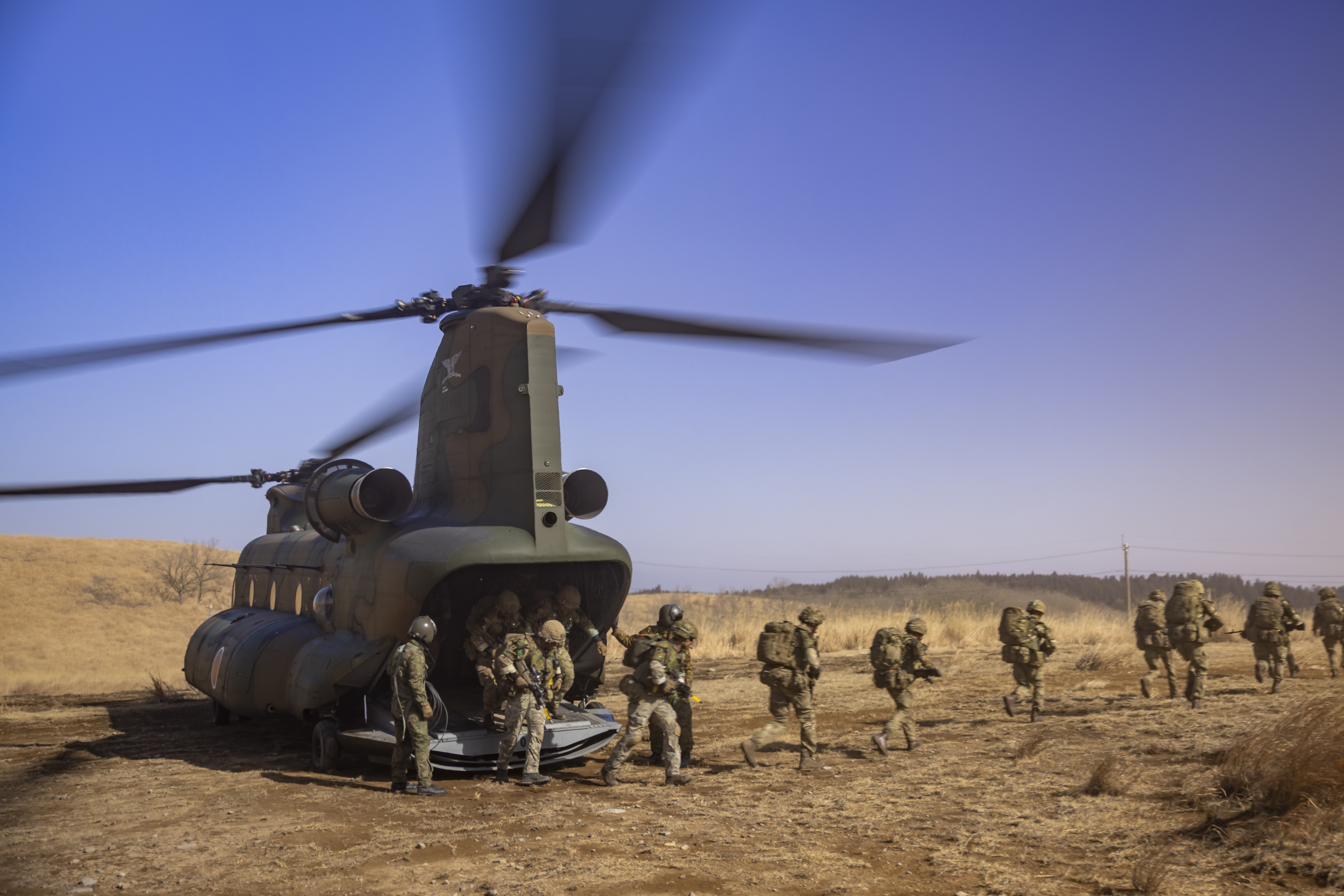 Multiple soldiers from the Parachute Regiment are seen disembarking a Japanese CH47 as it landed on on landing zone, they are running out of shot once they disembark
