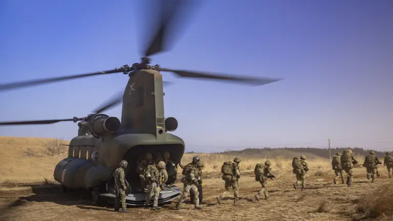 Multiple soldiers from the Parachute Regiment are seen disembarking a Japanese CH47 as it landed on on landing zone, they are running out of shot once they disembark