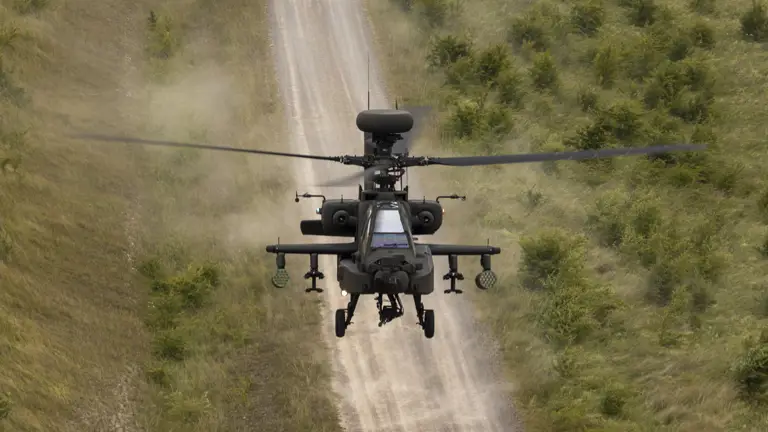 An Army helicopter is pictured flying above a dirt track.