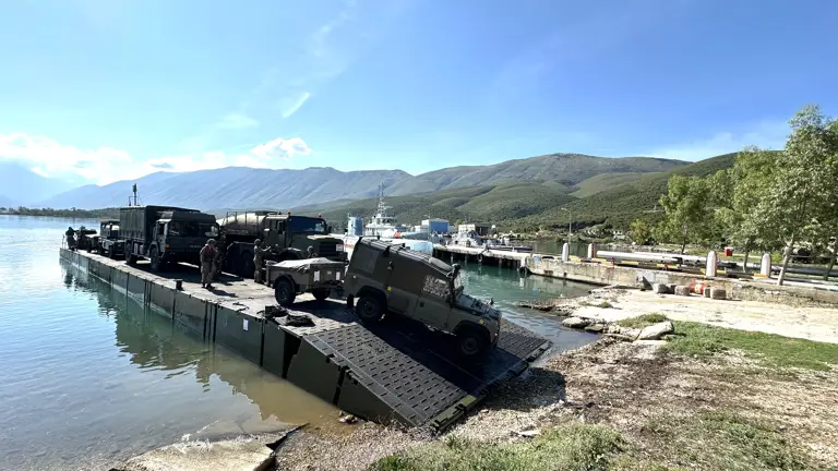 A Land Rover drives off a green military ferry.