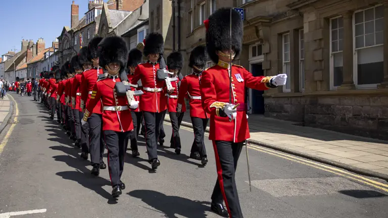 Soldiers in red tunics and black bearskin hats march through Berwick-upon-Tweed.