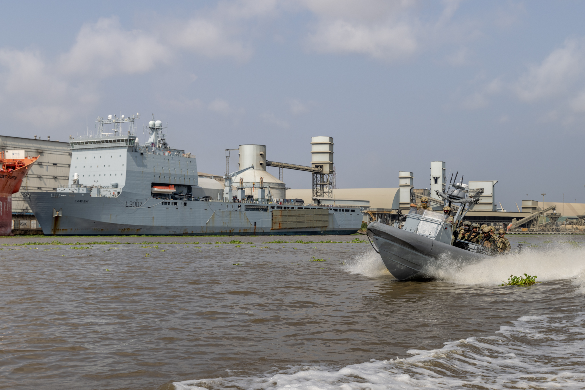 A large ship is docked in the background, a smaller boat can be seen in the foreground. 