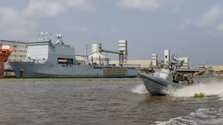 A large ship is docked in the background, a smaller boat can be seen in the foreground.