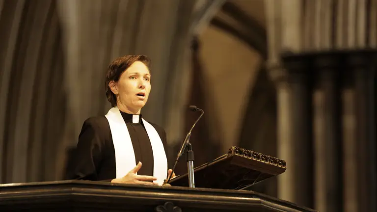 A woman delivers a sermon, she is wearing Christian religious dress.