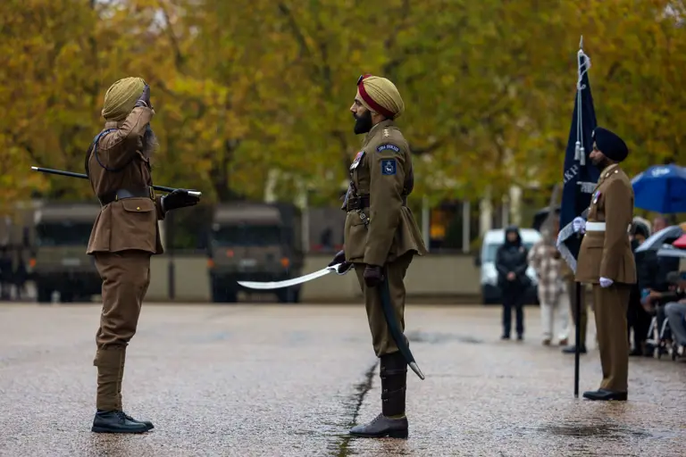Two soldiers in brown uniforms face each other during a formal salute.