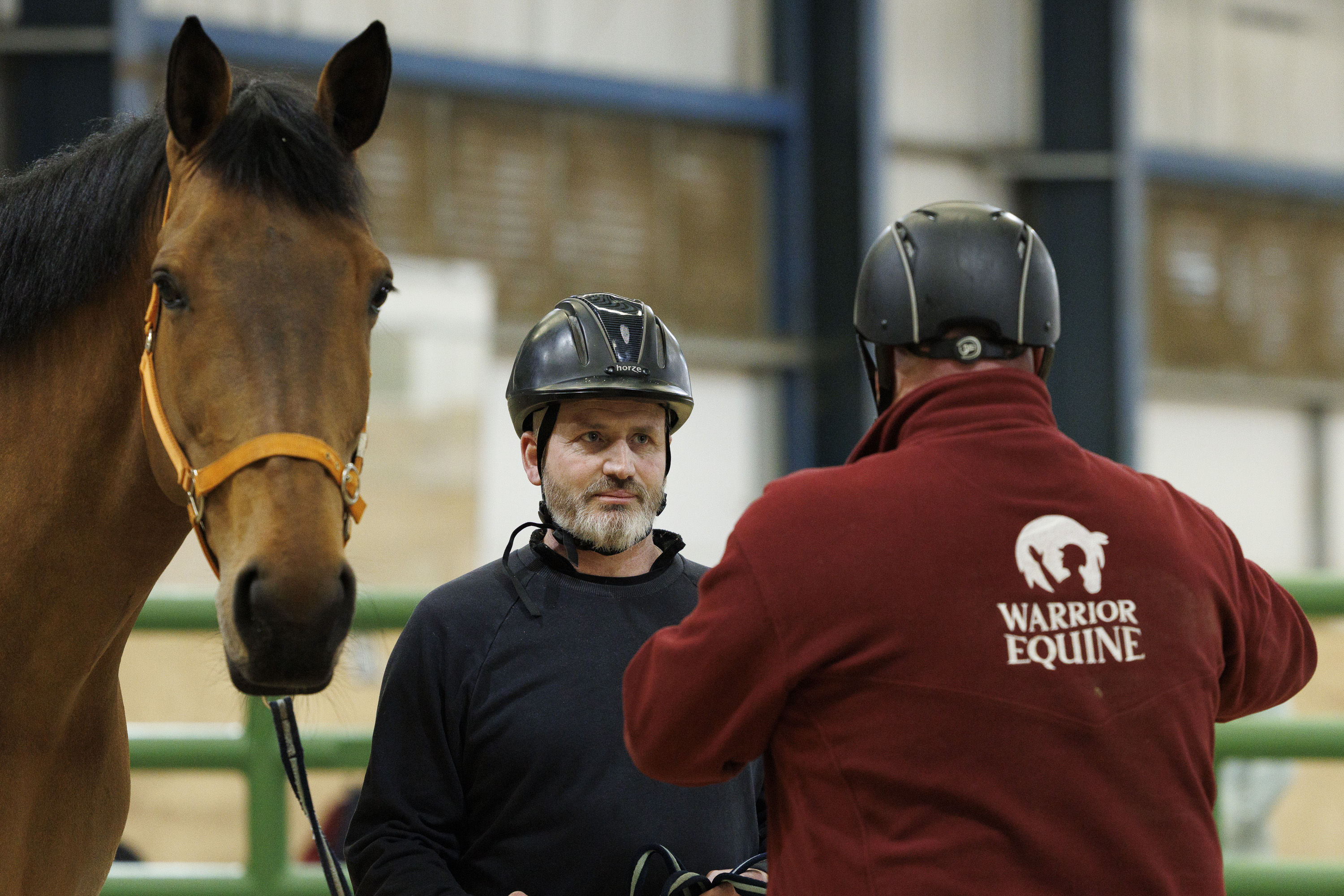A person holding a horse stands opposite another person wearing a 