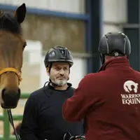 A person holding a horse stands opposite another person wearing a