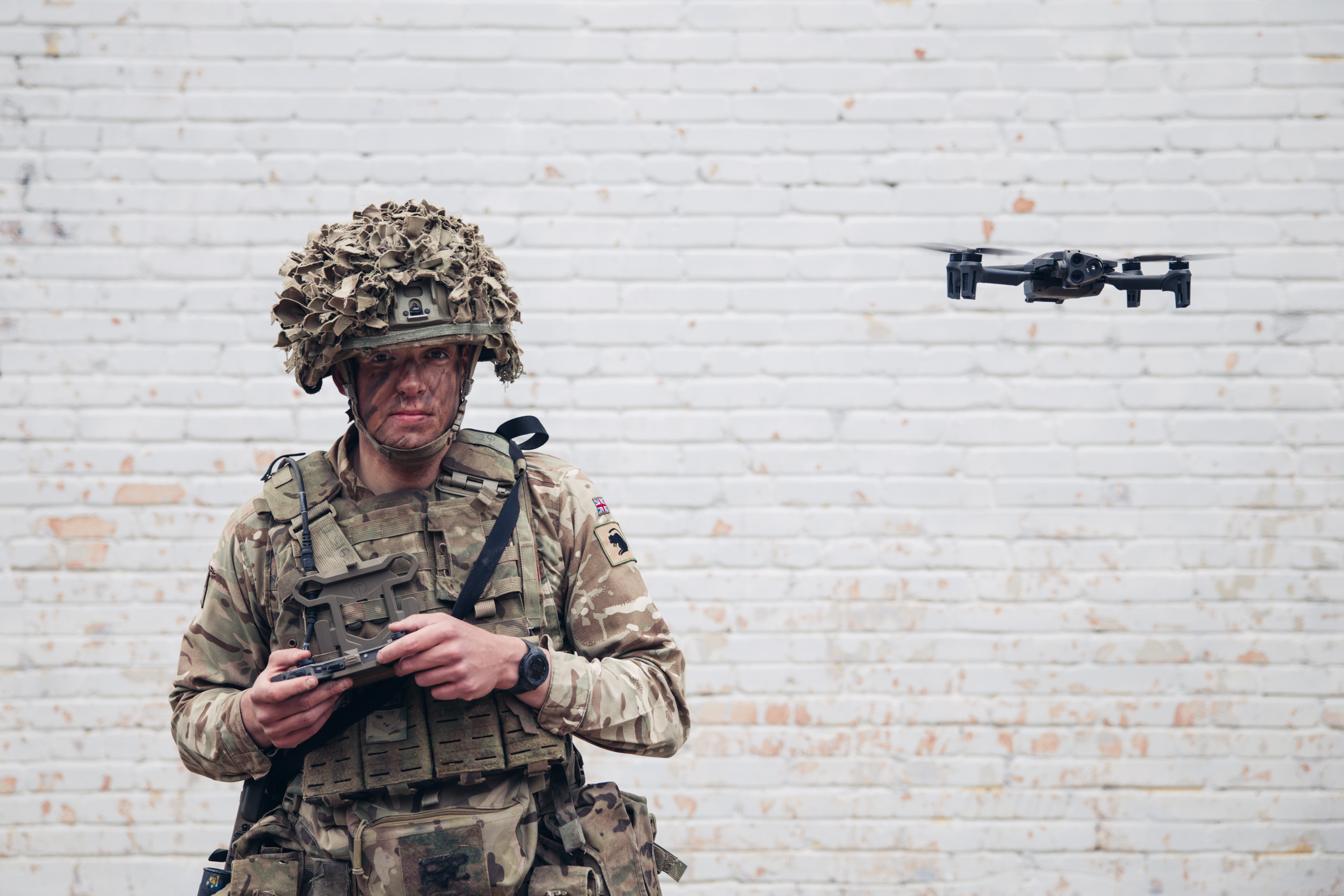 soldier wearing camouflage, helmet and cam cream across their face is seen operating a parrot drone during Exercise Hedgehog in Estonia.