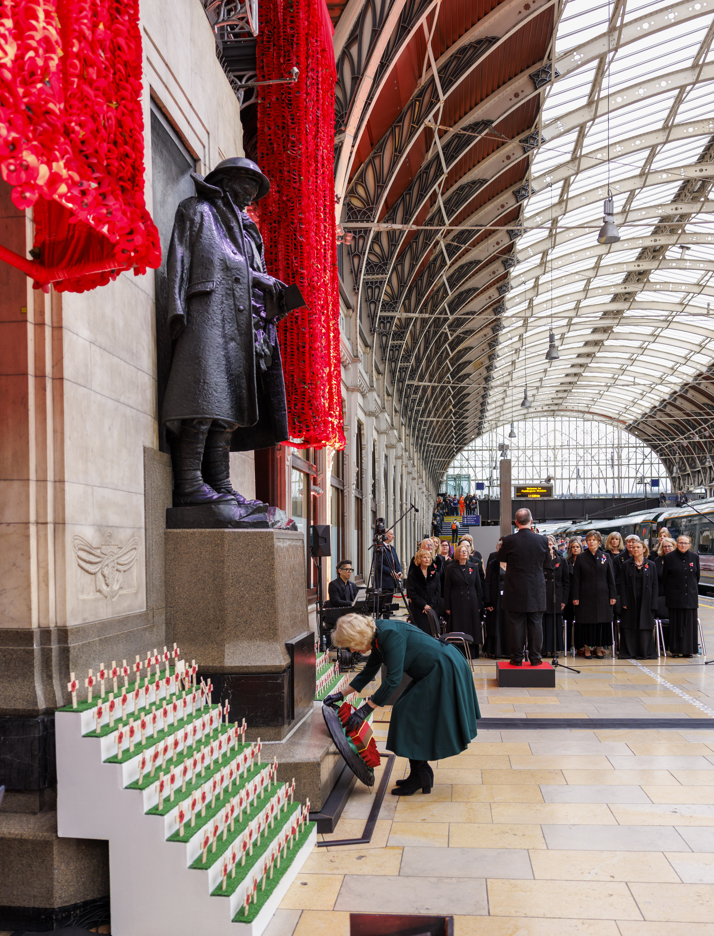 Her Majesty the Queen lays a wreath at a memorial. She is wearing a green dress. 