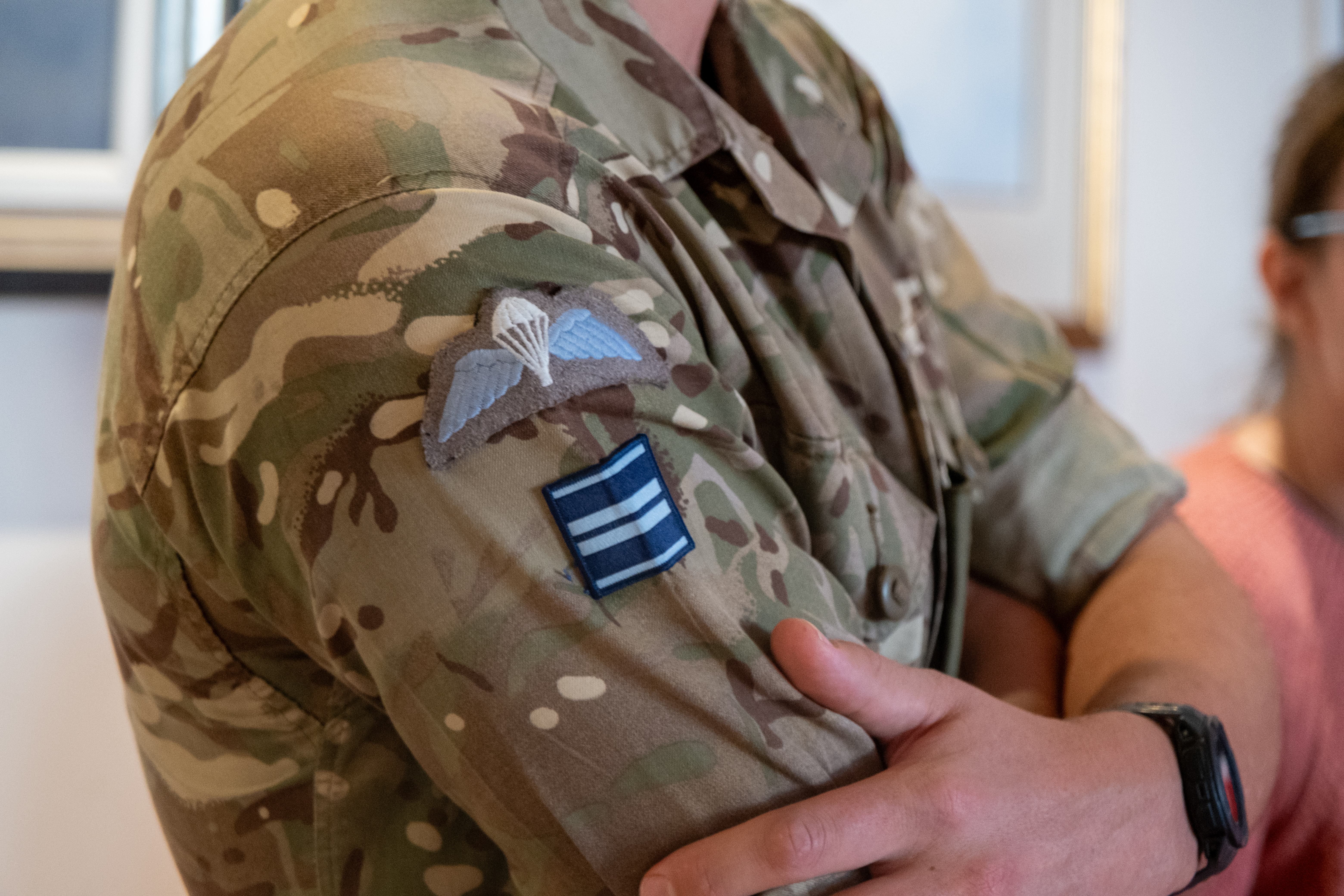 Close-up of a soldier's arm in camouflage uniform displaying an airborne patch on the sleeve.