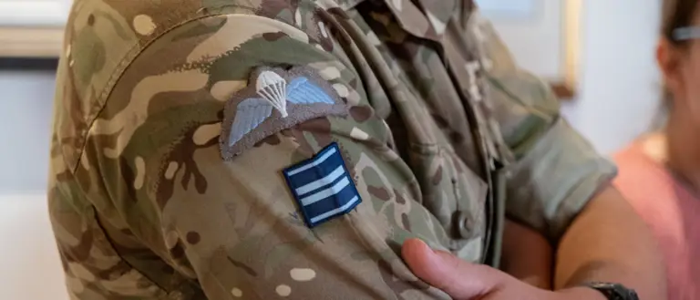 Close-up of a soldier's arm in camouflage uniform displaying an airborne patch on the sleeve.