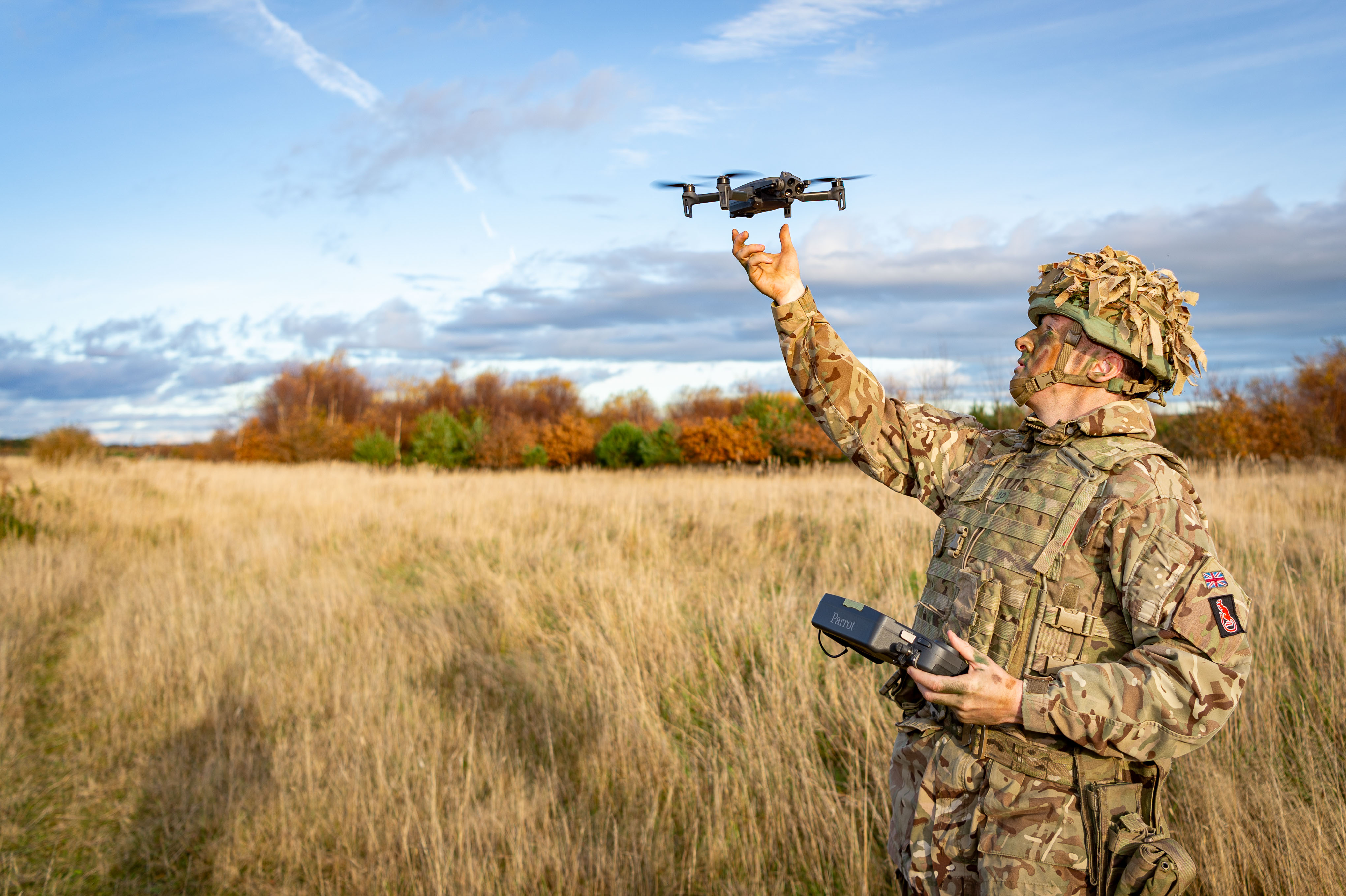 A man in uniform is pictured throwing a drone. 