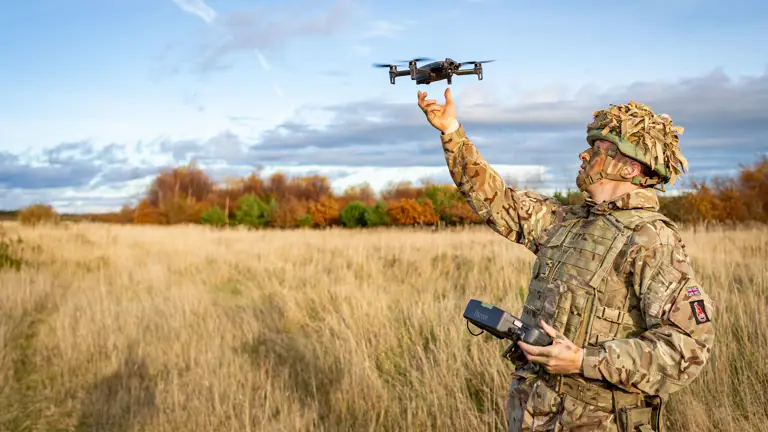 A man in uniform is pictured throwing a drone.