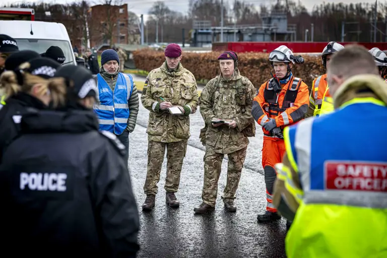 Group of uniformed personnel including police, military, and safety officers gathered outdoors for a briefing.