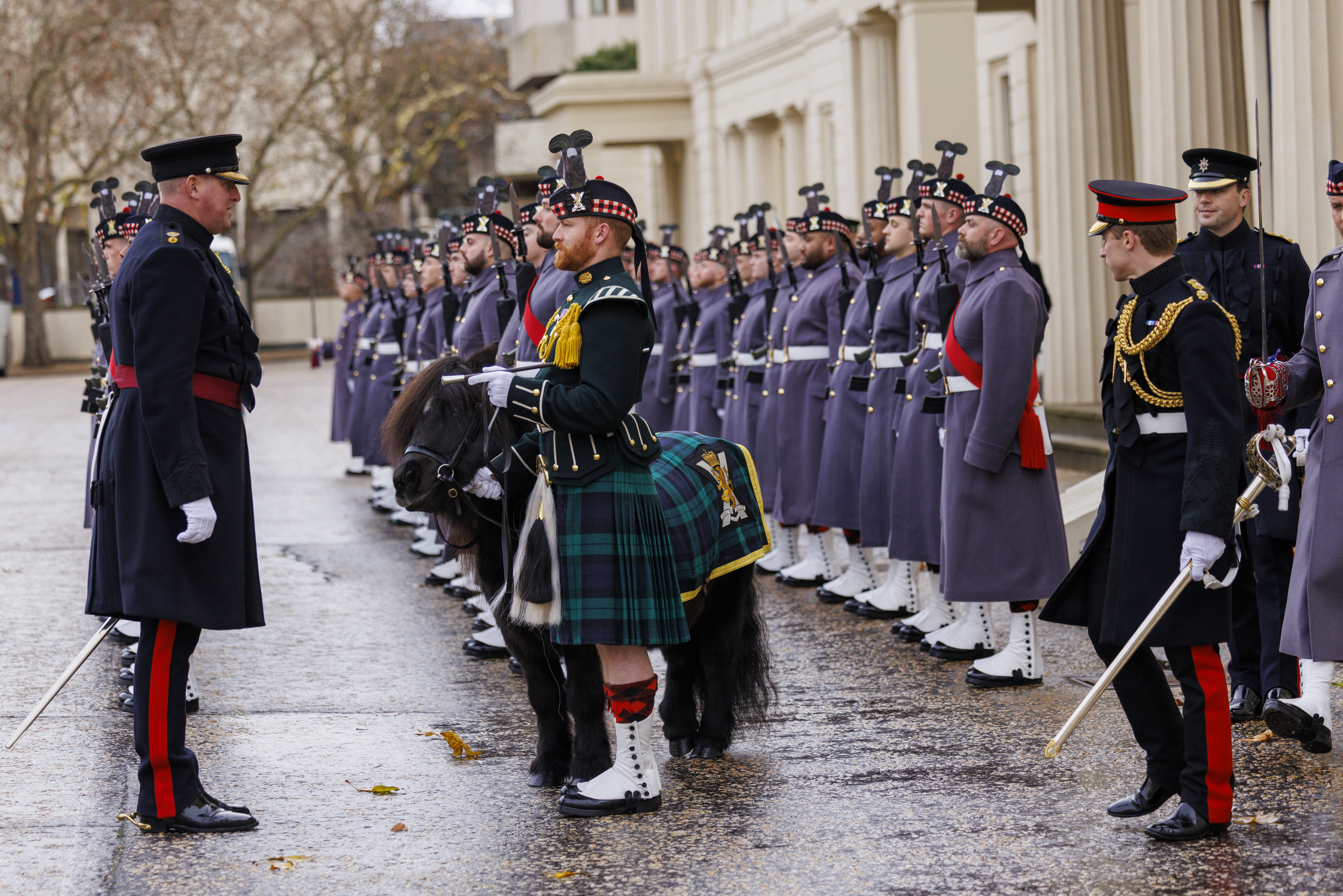 A line of uniformed guards standing at attention outside of a historic building.