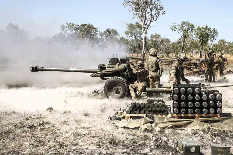 Soldiers fire an artillery piece.