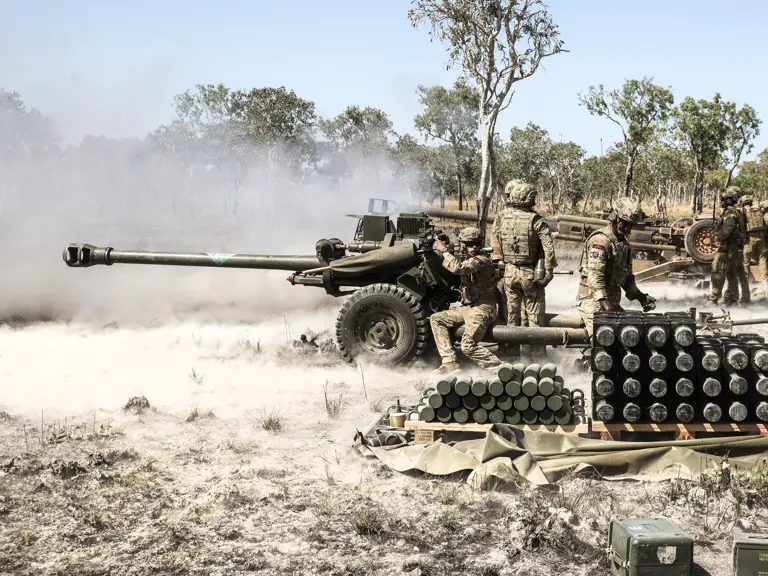 Soldiers fire an artillery piece.