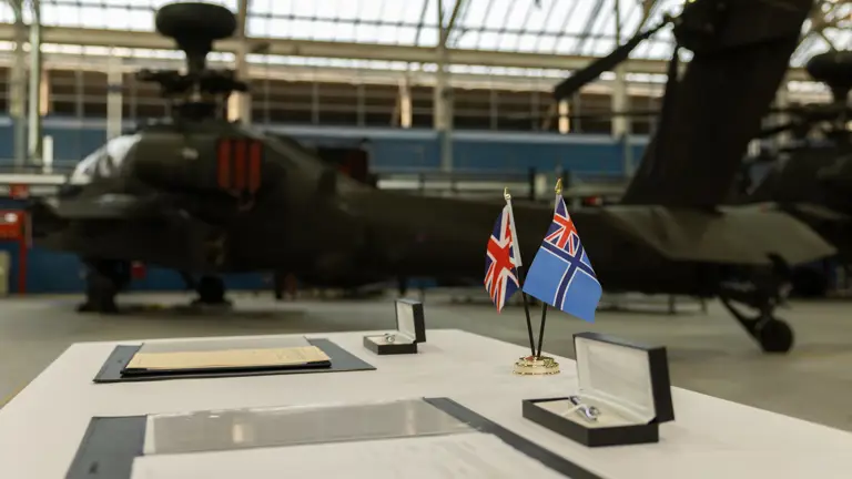 Some documents and flags sit on a table in front of a green military helicopter.