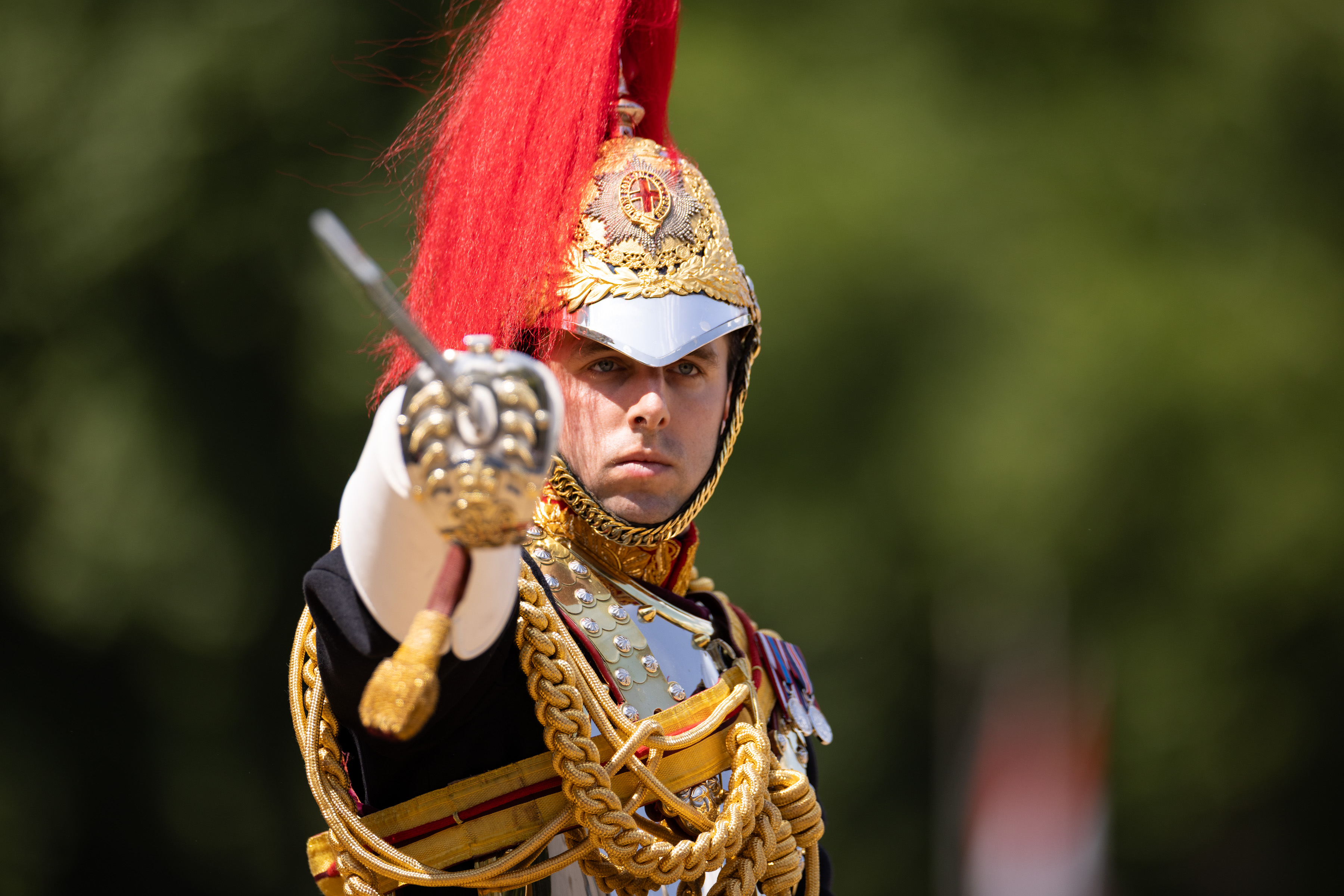 A soldier in black ceremonial attire points his swords towards the camera.