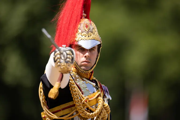 A soldier in black ceremonial attire points his swords towards the camera.