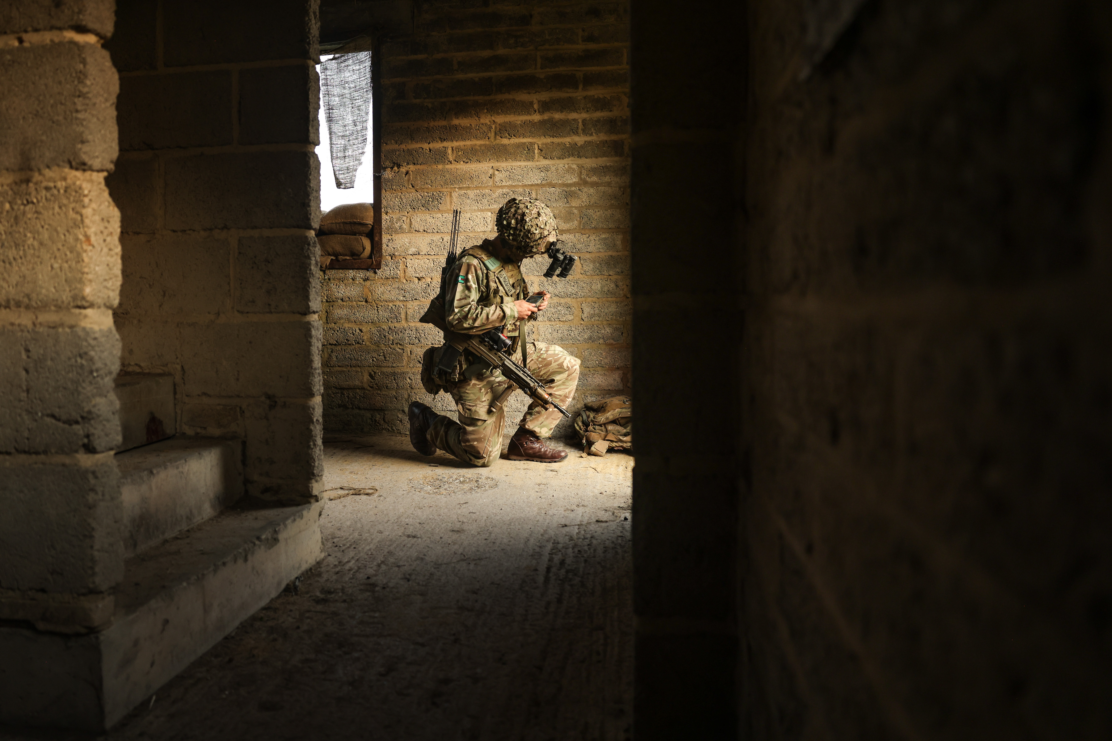 A man kneels in a building whilst controlling a drone.
