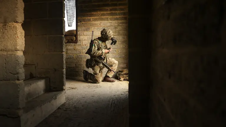 A man kneels in a building whilst controlling a drone.
