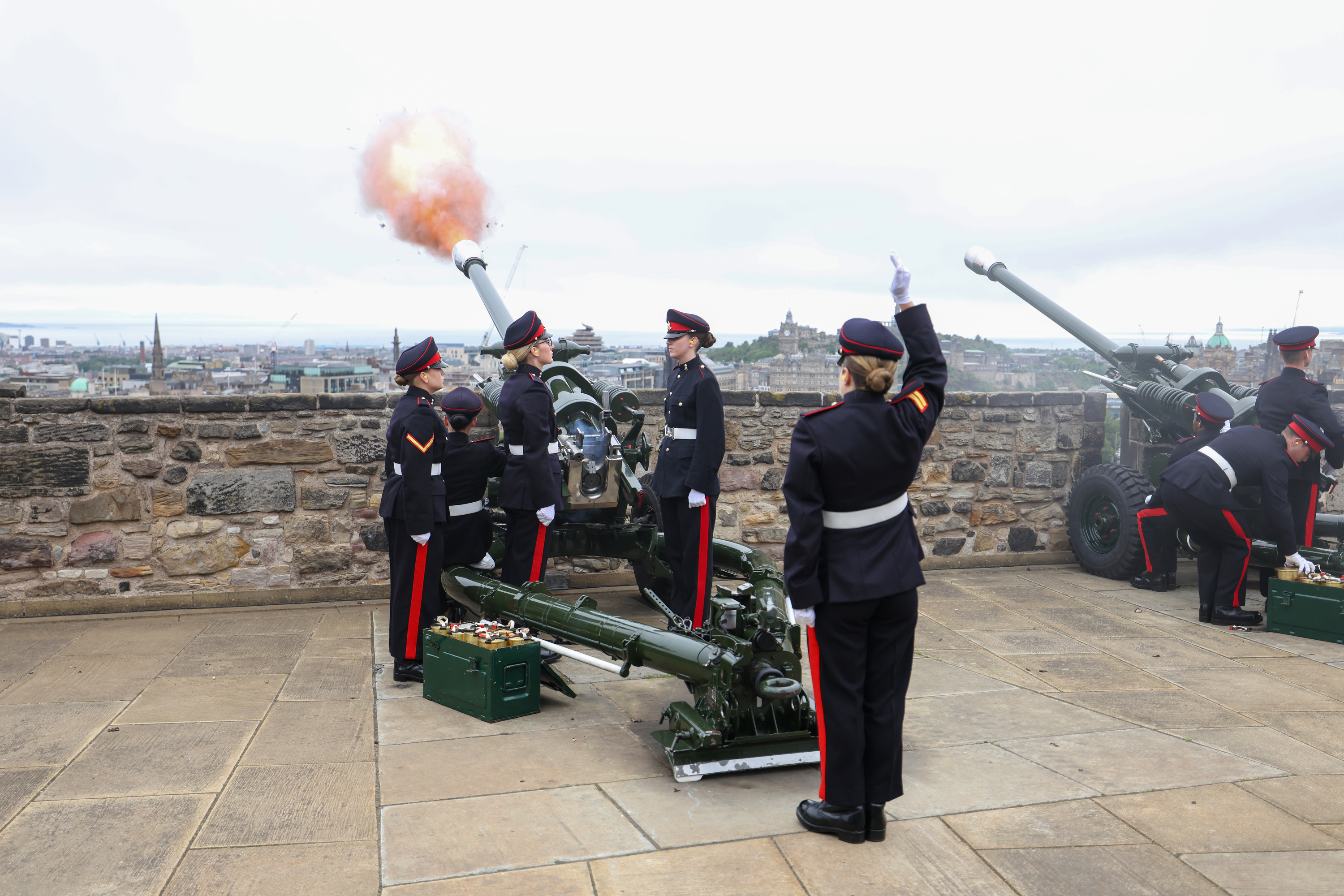 Several soldiers stand by as artillery is fired from a castle.