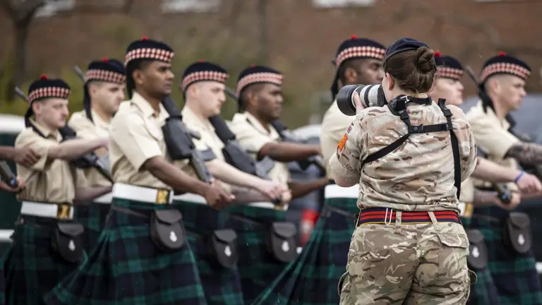 A British Army photographer takes photos on her Canon 1D Mark 3 of soldiers from a Scottish regiment as they march past.