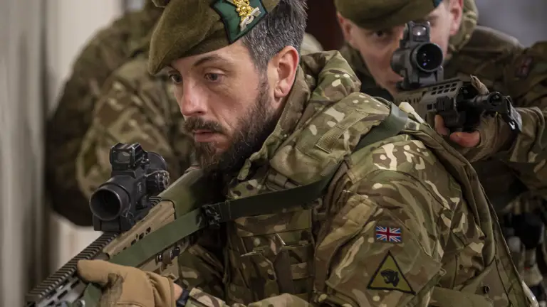 Two soldiers in uniform are pictured with their weapons drawn.
