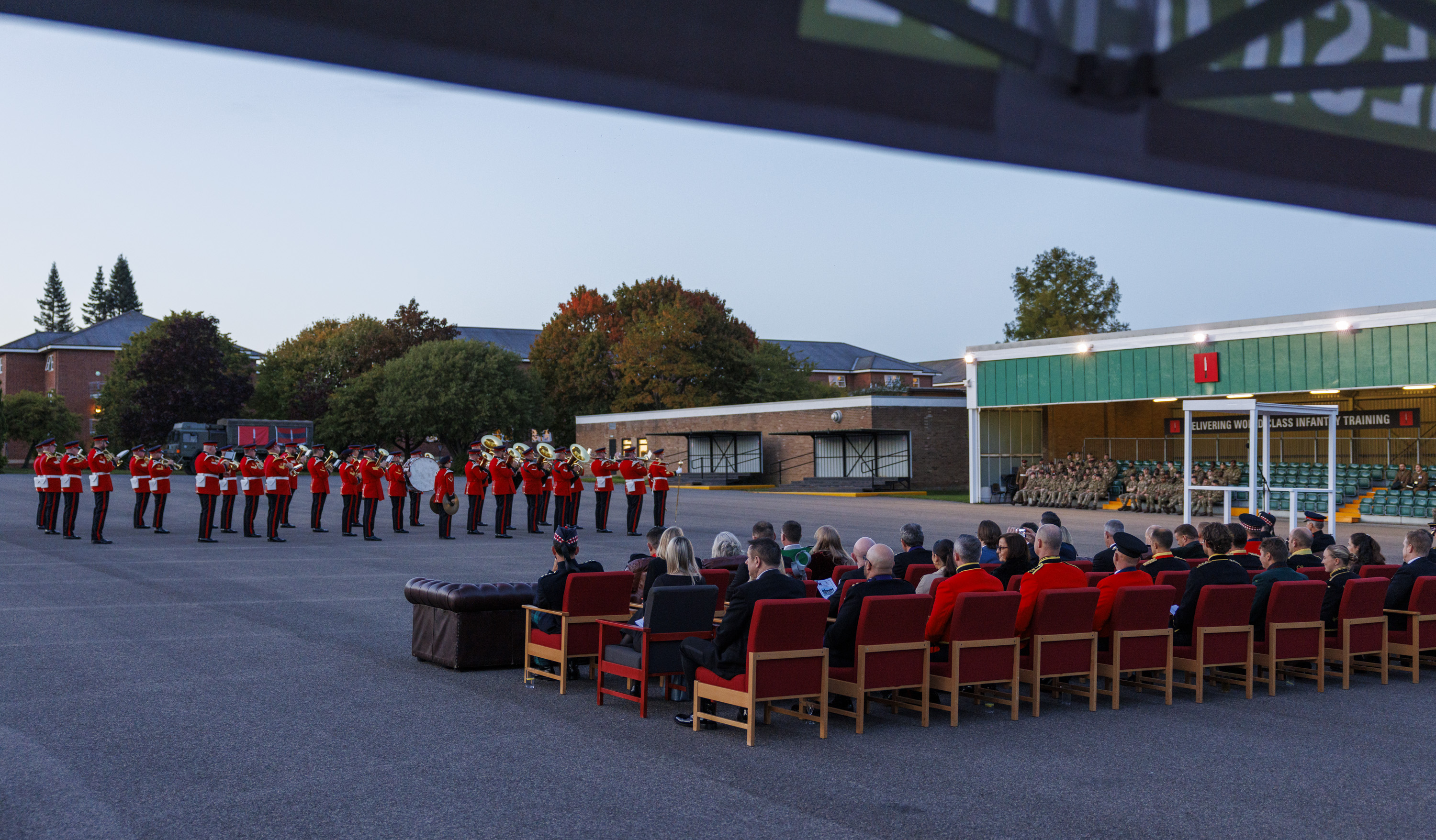An Army band in red and black ceremonial uniform playing instruments. 