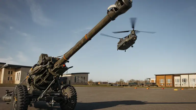 Artillery weapon is waiting to be attached the the underslung of a chinook flying into barracks for transport.