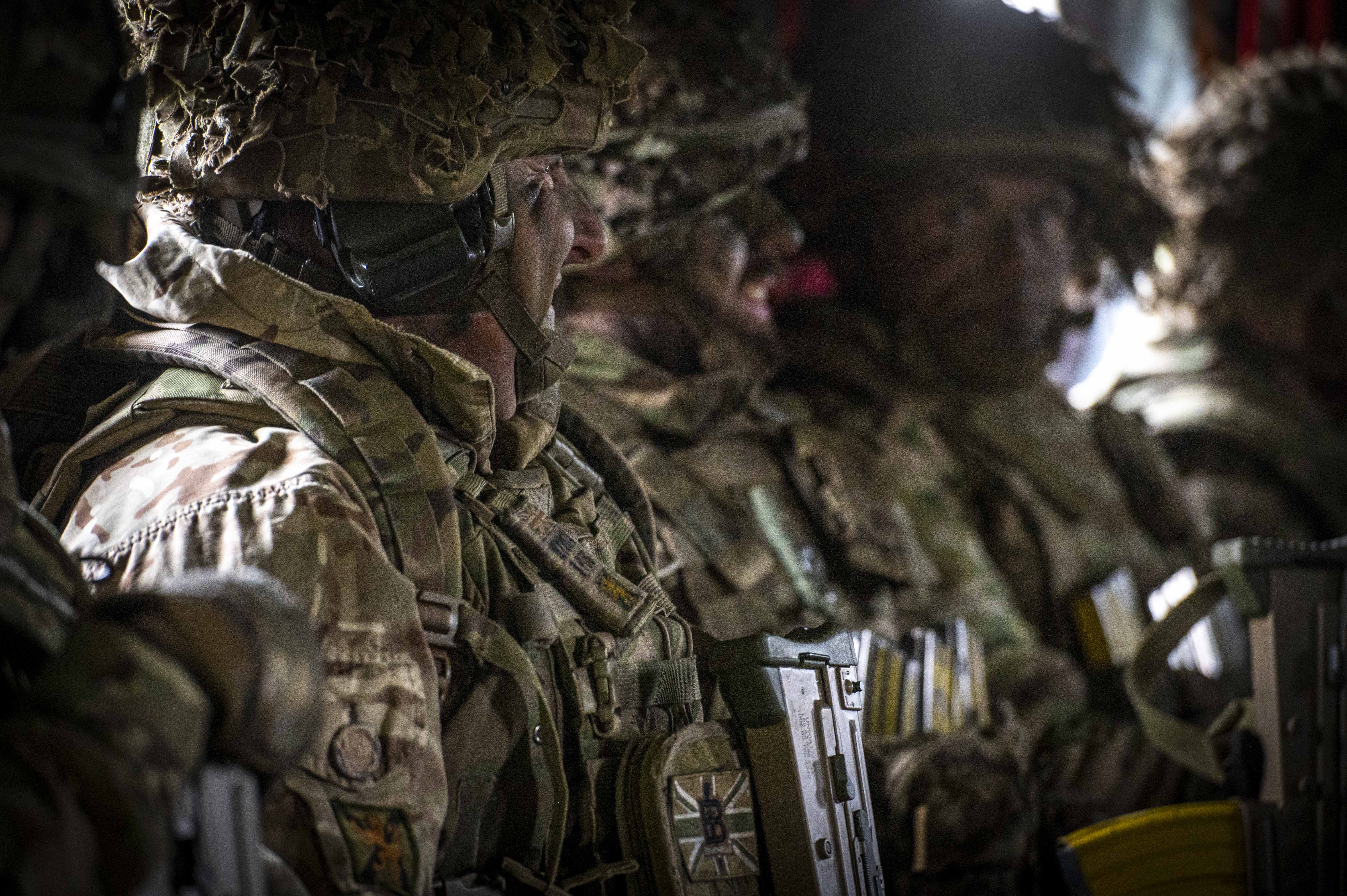 Three soldiers in camouflage uniform seen sitting in a Chinook.