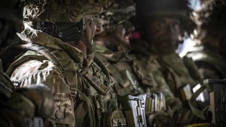 Three soldiers in camouflage uniform seen sitting in a Chinook.
