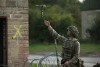 A man in uniform launches a drone into the sky.