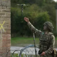A man in uniform launches a drone into the sky.
