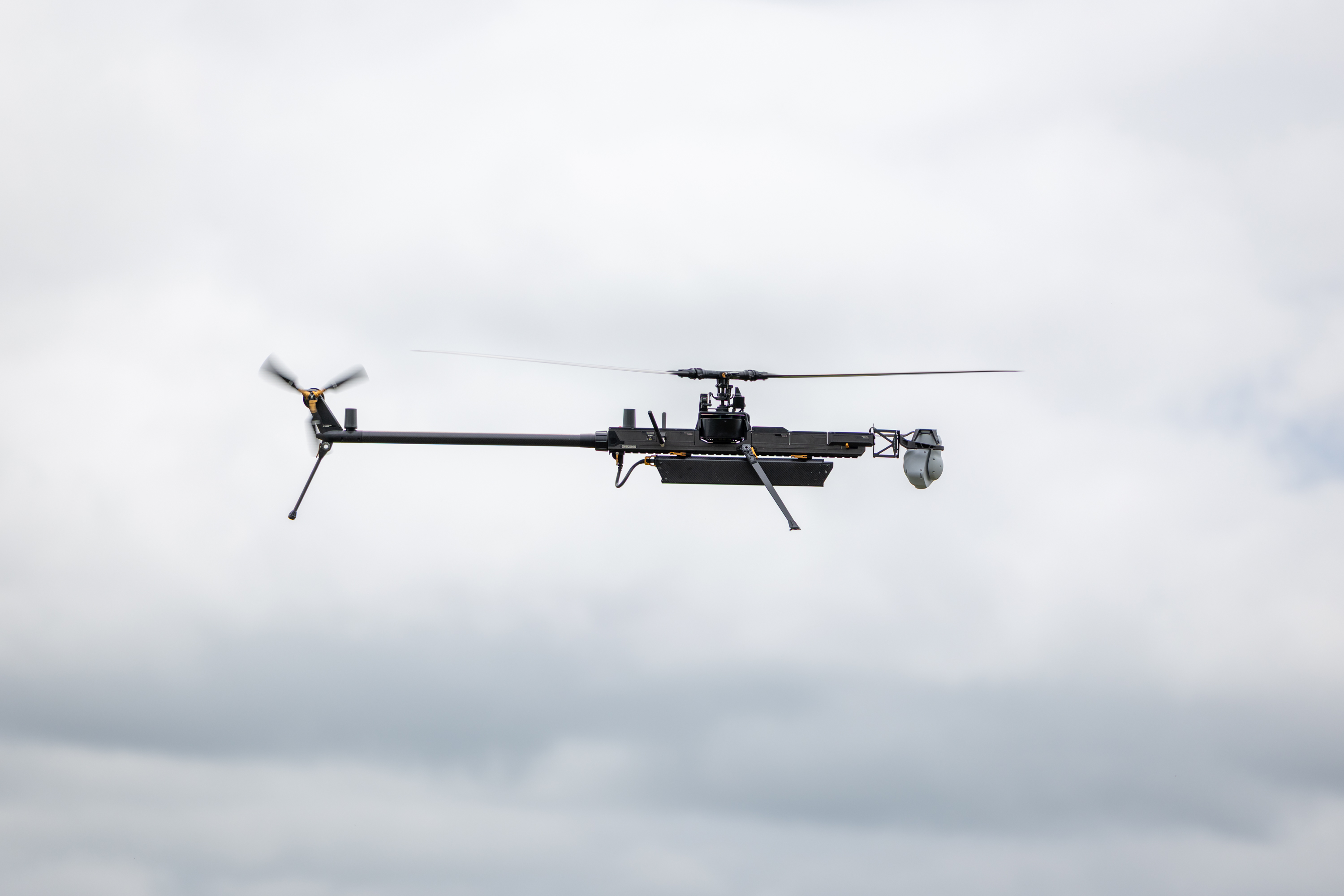 A drone is flying against a cloudy sky backdrop.