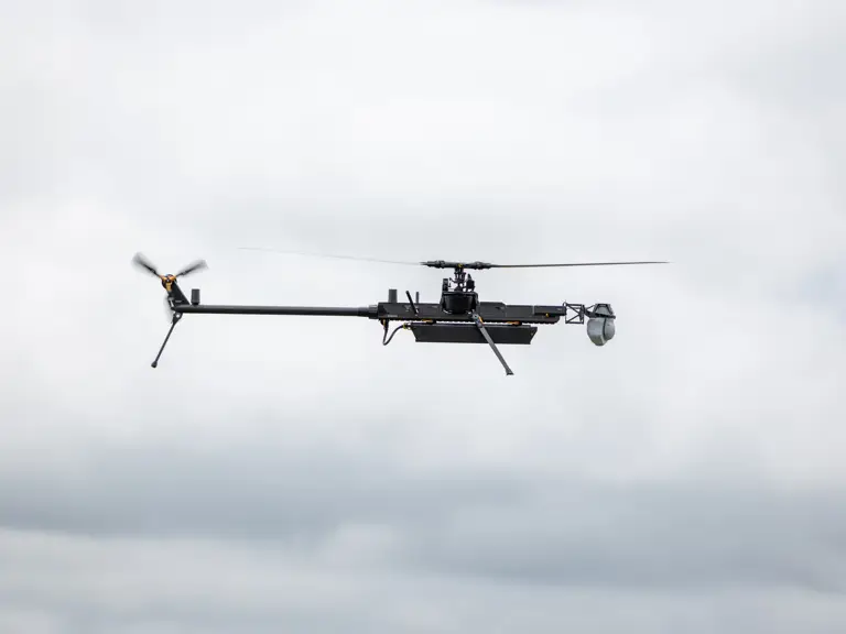 A drone is flying against a cloudy sky backdrop.