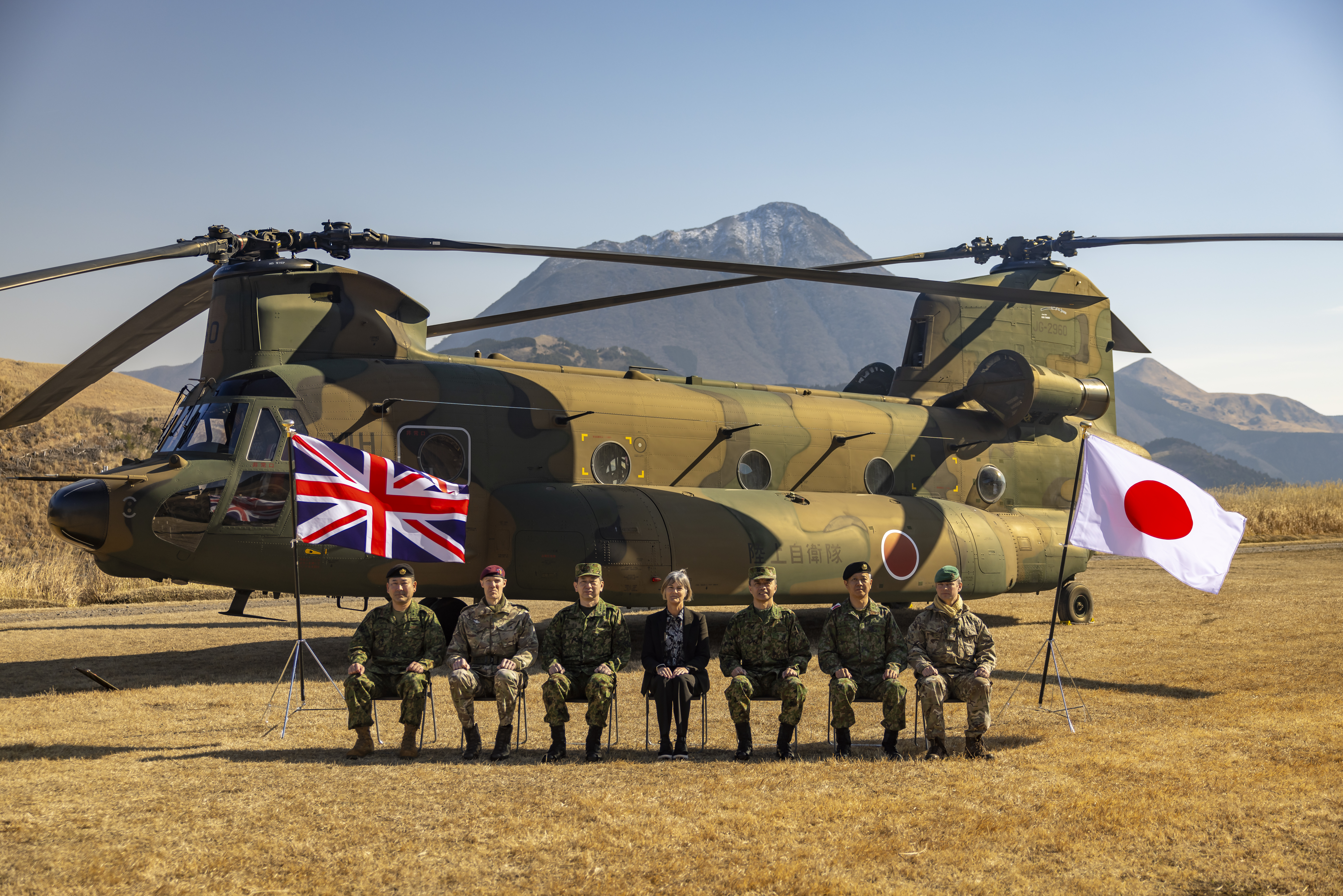 Group photo of distinguished guests (left to right) Major General Wakamatsu, 1st Airborne Brigade Commander; Brigadier Mark Berry, Commander of 16 Air Assault Brigade; General Morishita, Chief of Staff of Japanese Ground Self Defence Force; Julia Longbottom, UK Ambassador to Japan; Lieutenant General Togashi, Commander of Eastern Army; Major General Maejima, Commander of 12th Brigade; and Major Dan Ward, UK assistant defence attache in Japan. The Union Jack on the left and Japan's flag is on the right. 