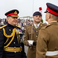 Chief of the General Staff in his blues uniform is photographed inspecting a soldier in their brown uniform while smiling.
