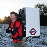 Major Joss Mowforth, pictured in his workout clothes posing for a portrait outside in snowy weather carrying a fridge strapped to his back.