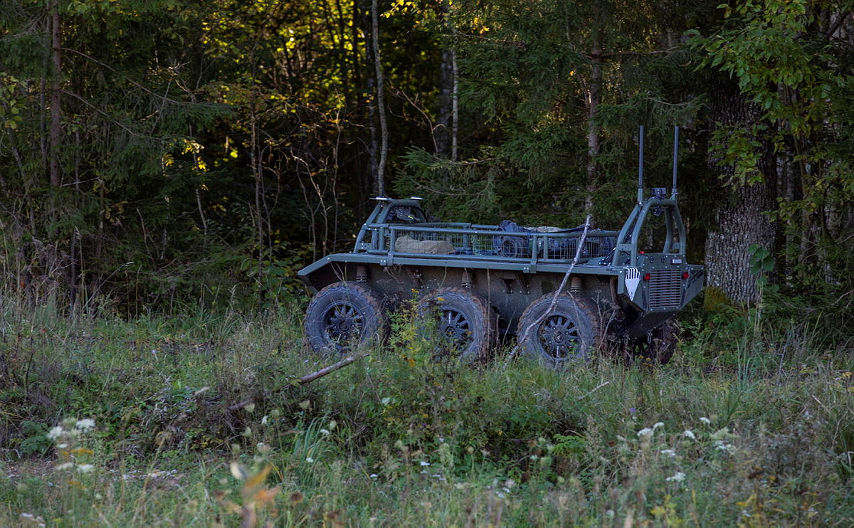 An unmanned resupply vehicle shown in the woodlands completely unmanned and delivering supplies to the soldiers in the woods.